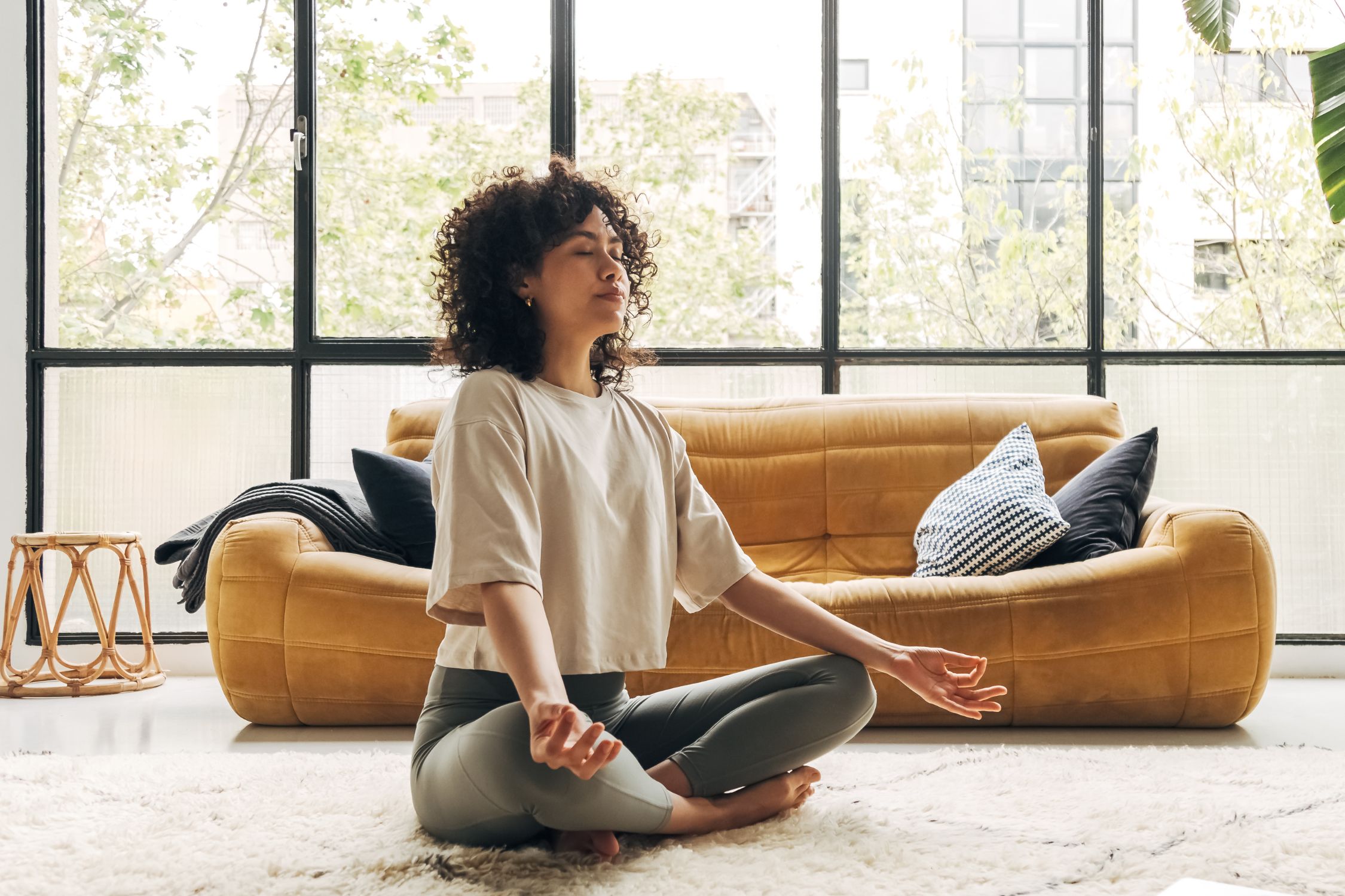 Frau meditiert auf dem Boden sitzend, Meditation als Stressmanagement bei Rosacea