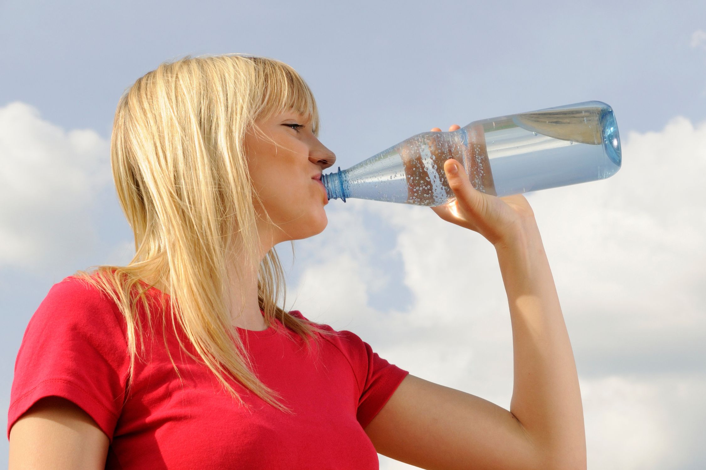Frau trinkt Wasser aus einer Flasche nach dem Sport