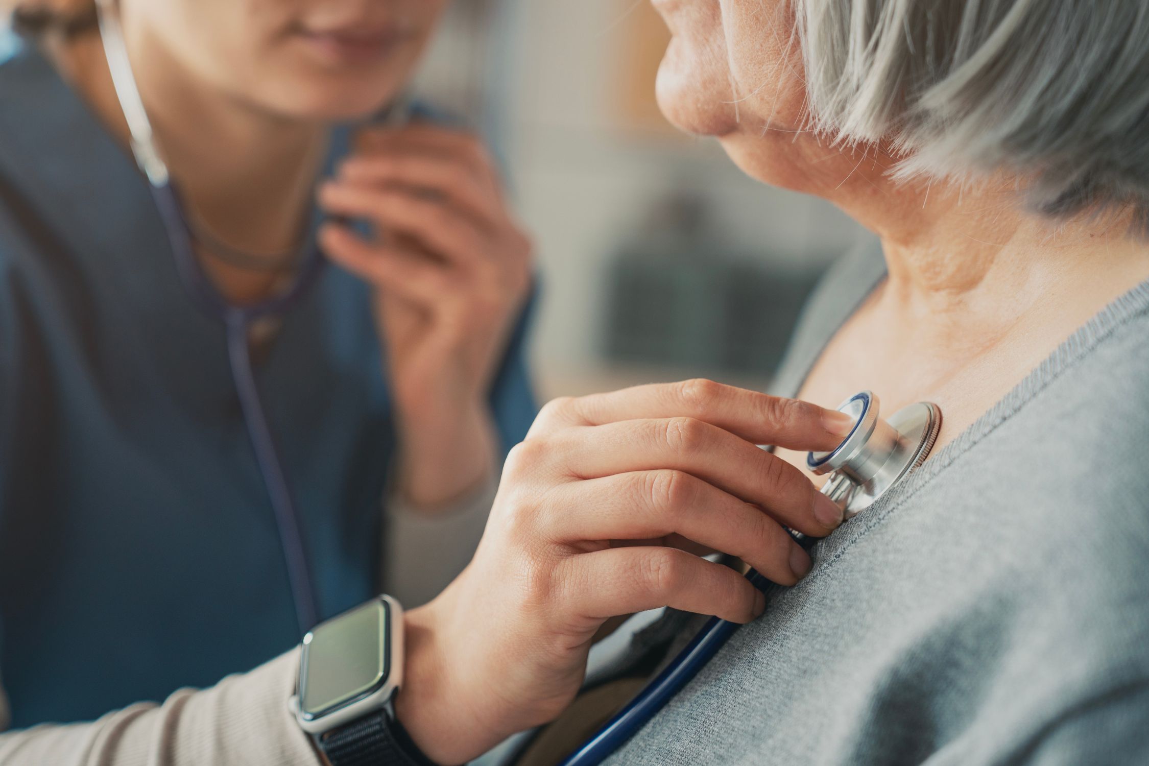 Ärztin hört die Brust einer Patientin mit dem Stethoskop ab