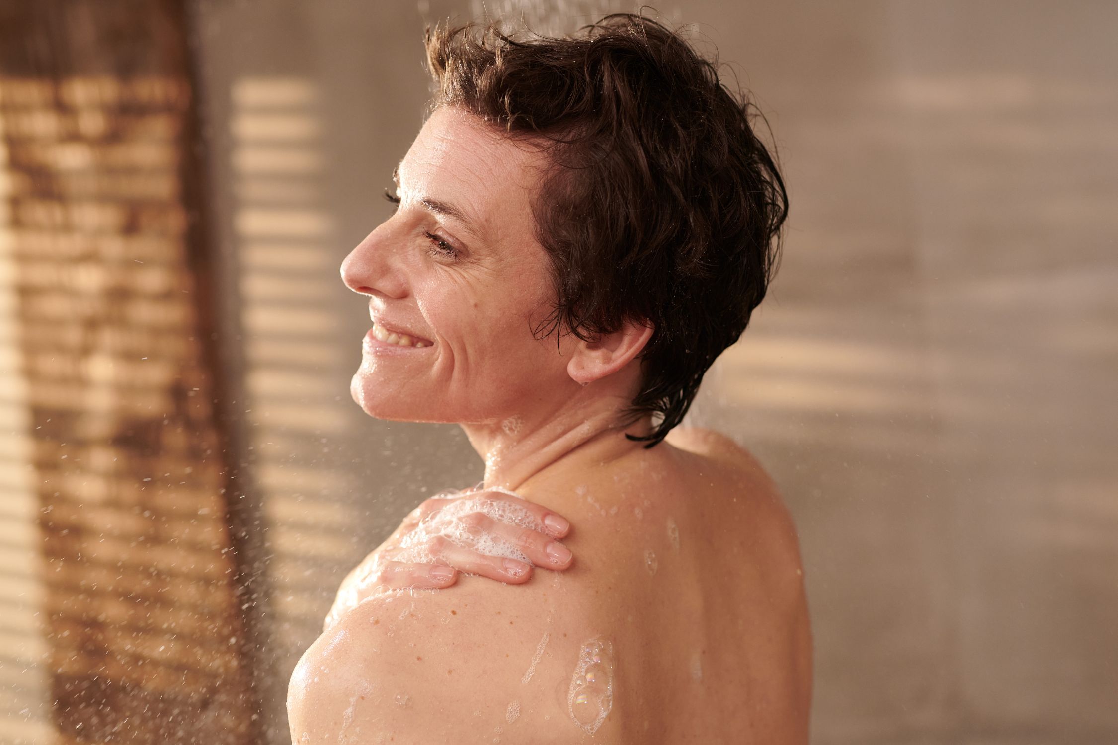 Frau in der Dusche schäumt sich den Körper ein