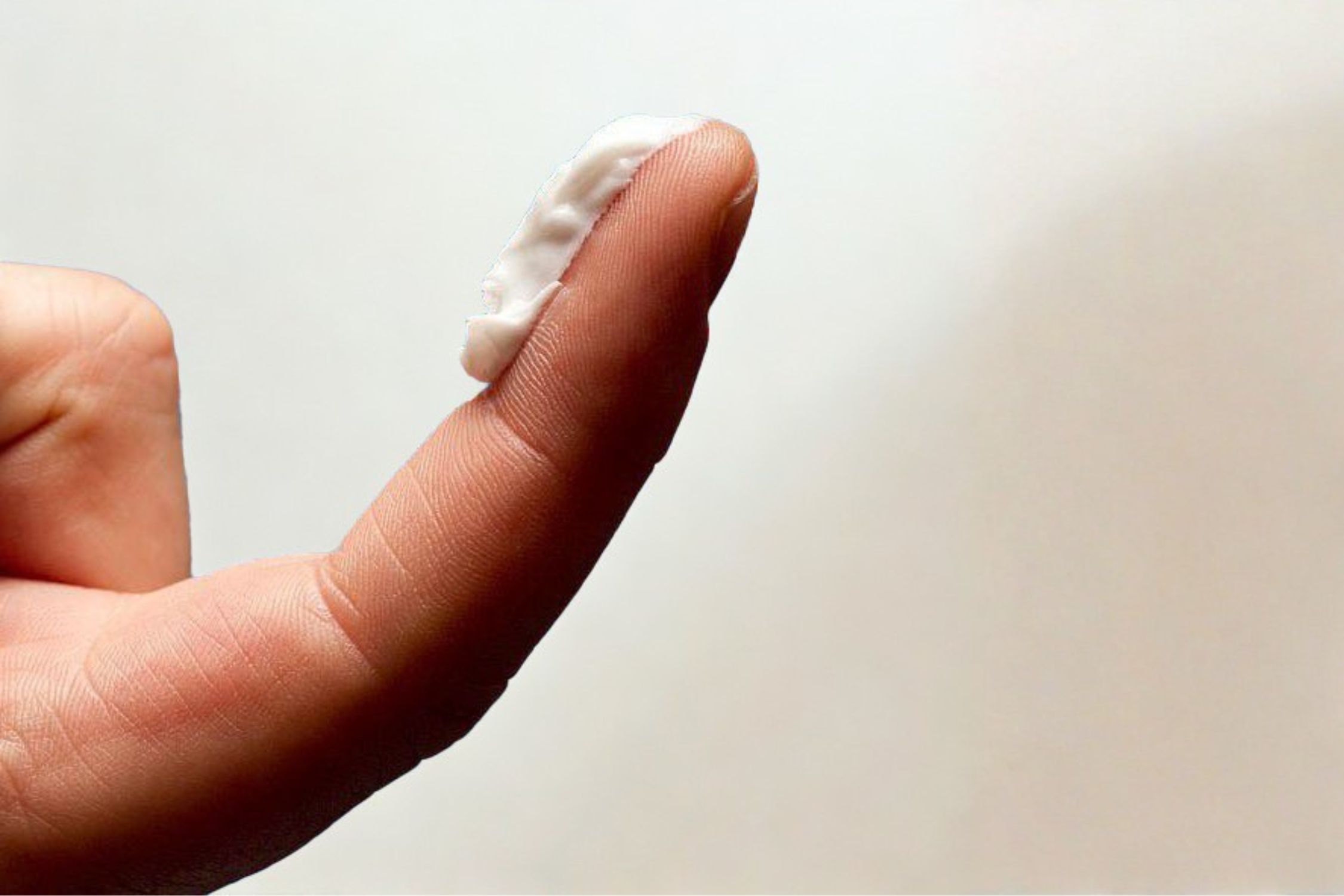 Eine Menge weißer Creme von der Fingerspitze bis zur ersten Gelenkfalte des Zeigefingers