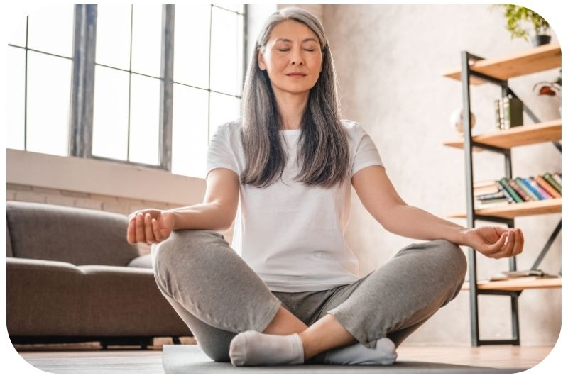 Frau meditiert in einer Yoga-Pose umgeben von einer ruhigen Umgebung