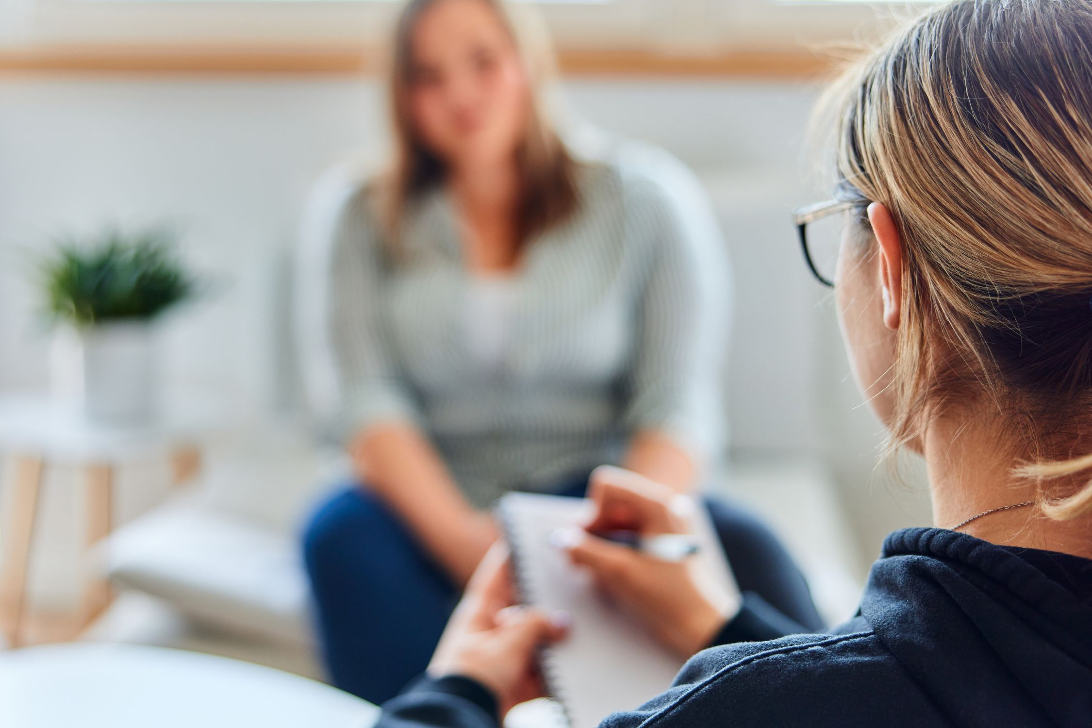 Frau im Gespräch mit Psychologin, die sich Notizen macht