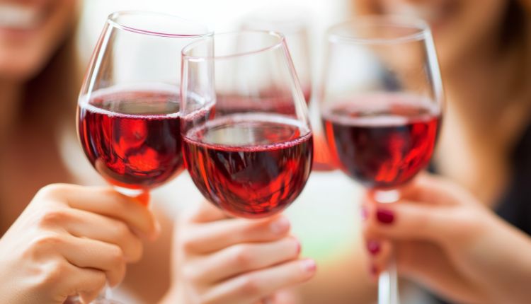 Drei Hände halten drei Gläser Rotwein zum Anstoßen hoch