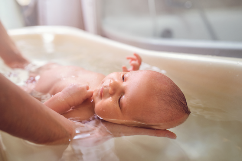 Baby wird in Badewanne gebadet