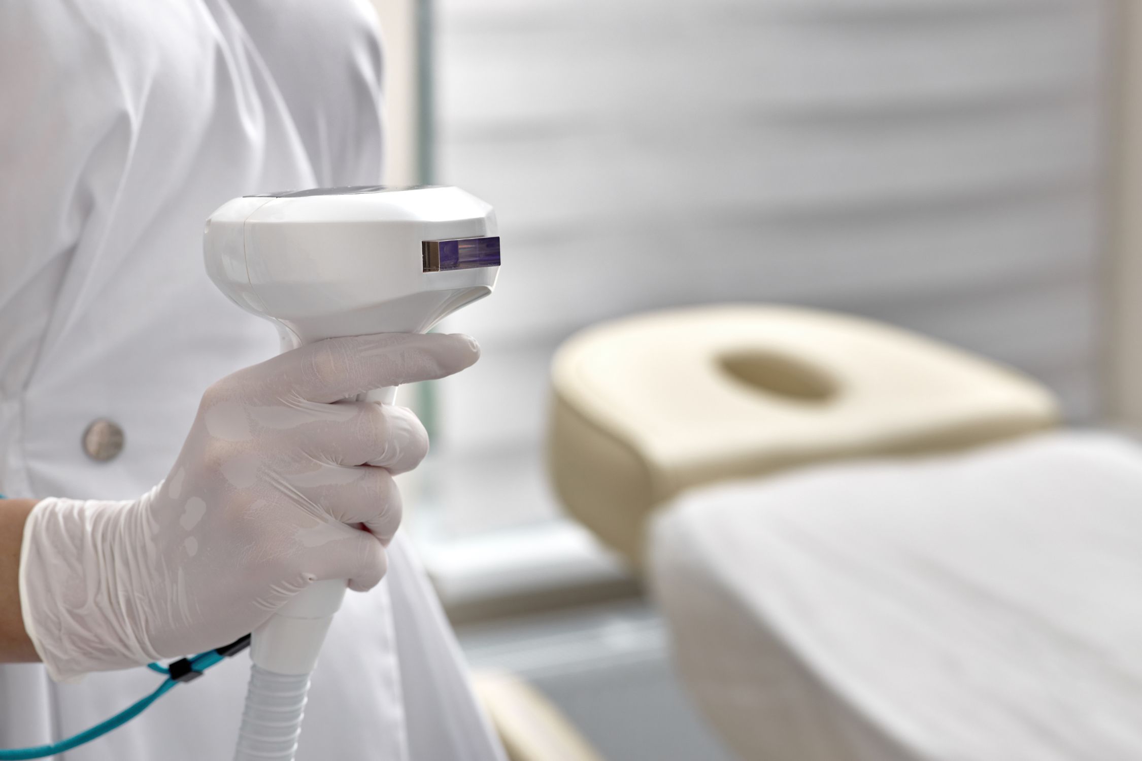 Dermatologin mit weißen Handschuhen hält IPL Gerät in der Hand